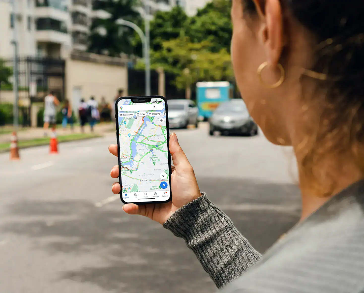 Person holding a smartphone on a city street, viewing a map application with navigation directions displayed on the screen—ideal for an Automotive PPC Agency looking to showcase seamless digital navigation and smart urban mobility solutions.